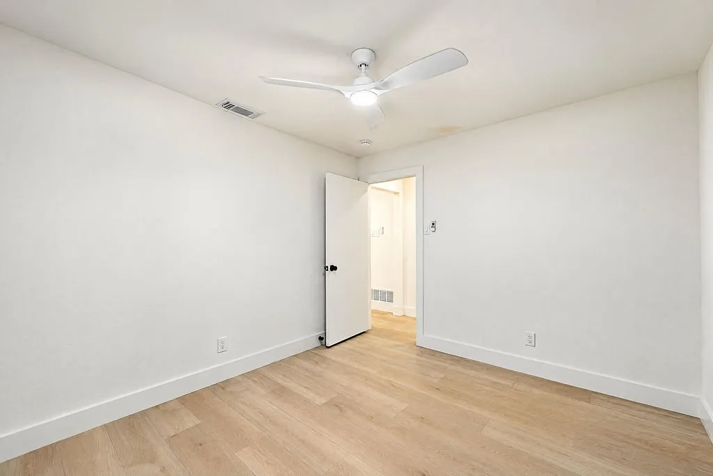 Wood-finish flooring with white baseboards and painted walls