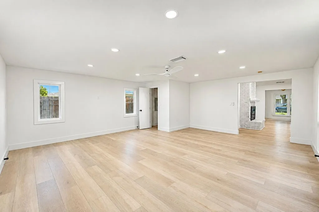 Recessed lighting illuminates the expansive interior featuring wood-finish flooring and a white ceiling fan