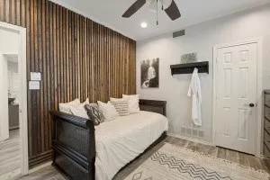 Feature wall with vertical wood paneling, wood-finish flooring, ceiling fan with integrated lighting, and recessed lighting
