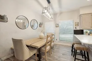 Vaulted ceilings with a linear chandelier, wood-finish flooring, and a large window with blinds