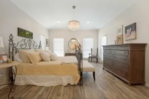 Spacious room with wood-finish flooring, vaulted ceiling, recessed lighting, and a crystal chandelier