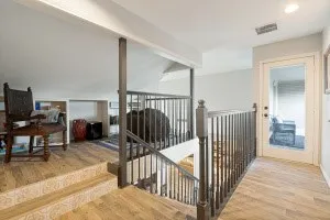 Wood-finish flooring, built-in shelving, glass-paneled door, and dark-finished stair railings