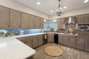 Spacious kitchen featuring light-toned cabinetry, light-colored countertops, stainless steel appliances, and wood-look flooring