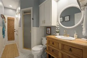 Wood vanity with undermount sink, brass-finish faucet, and circular mirror