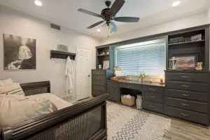 Built-in desk and storage cabinetry, recessed lighting, ceiling fan, window with blinds, and wood-finish flooring