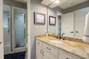 Vanity with a polished stone countertop, undermount sink, and dark bronze-finish fixtures