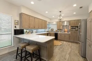 U-shaped kitchen with wood-finish flooring, light-toned cabinetry, stainless steel appliances, and recessed lighting