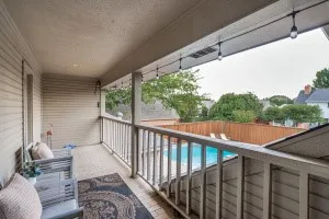 Covered balcony with wood-finish flooring and a balustrade railing