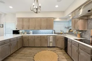 U-shaped kitchen featuring light wood-finish cabinetry, light countertops, wood-finish flooring, recessed lighting, and a chandelier