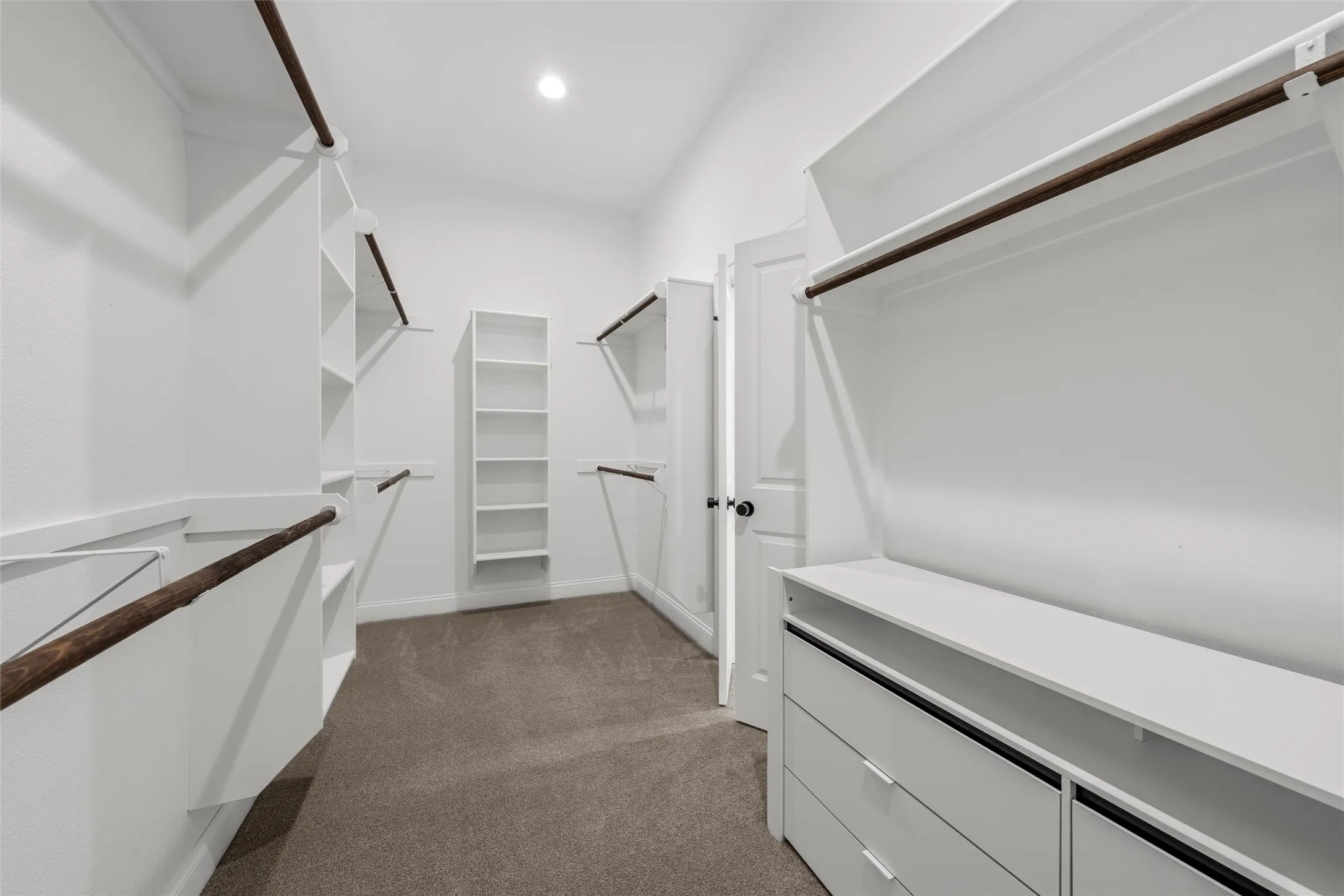 Walk-in closet with built-in shelving, hanging rods, and integrated drawers