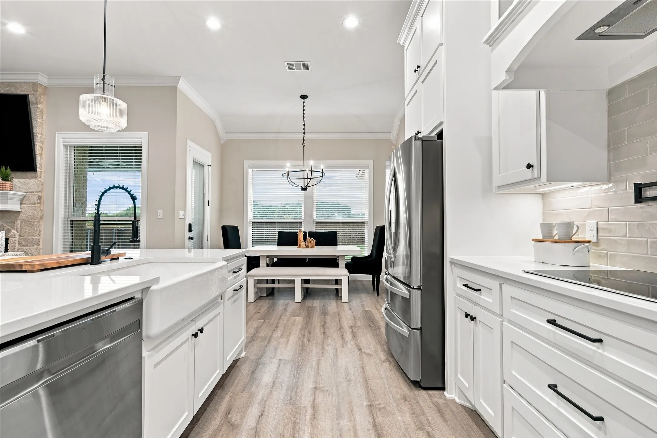 Open-concept kitchen with white shaker cabinetry, stainless steel appliances, and wood-finish flooring