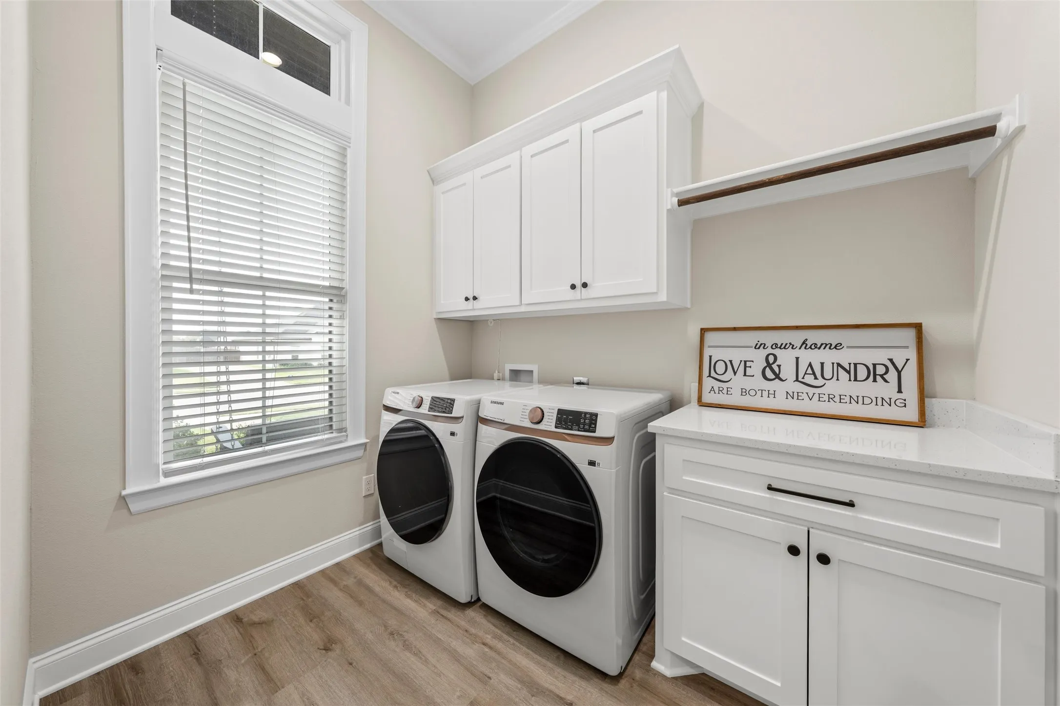 Built-in white cabinetry, wood-finish flooring, white window trim, and a white countertop