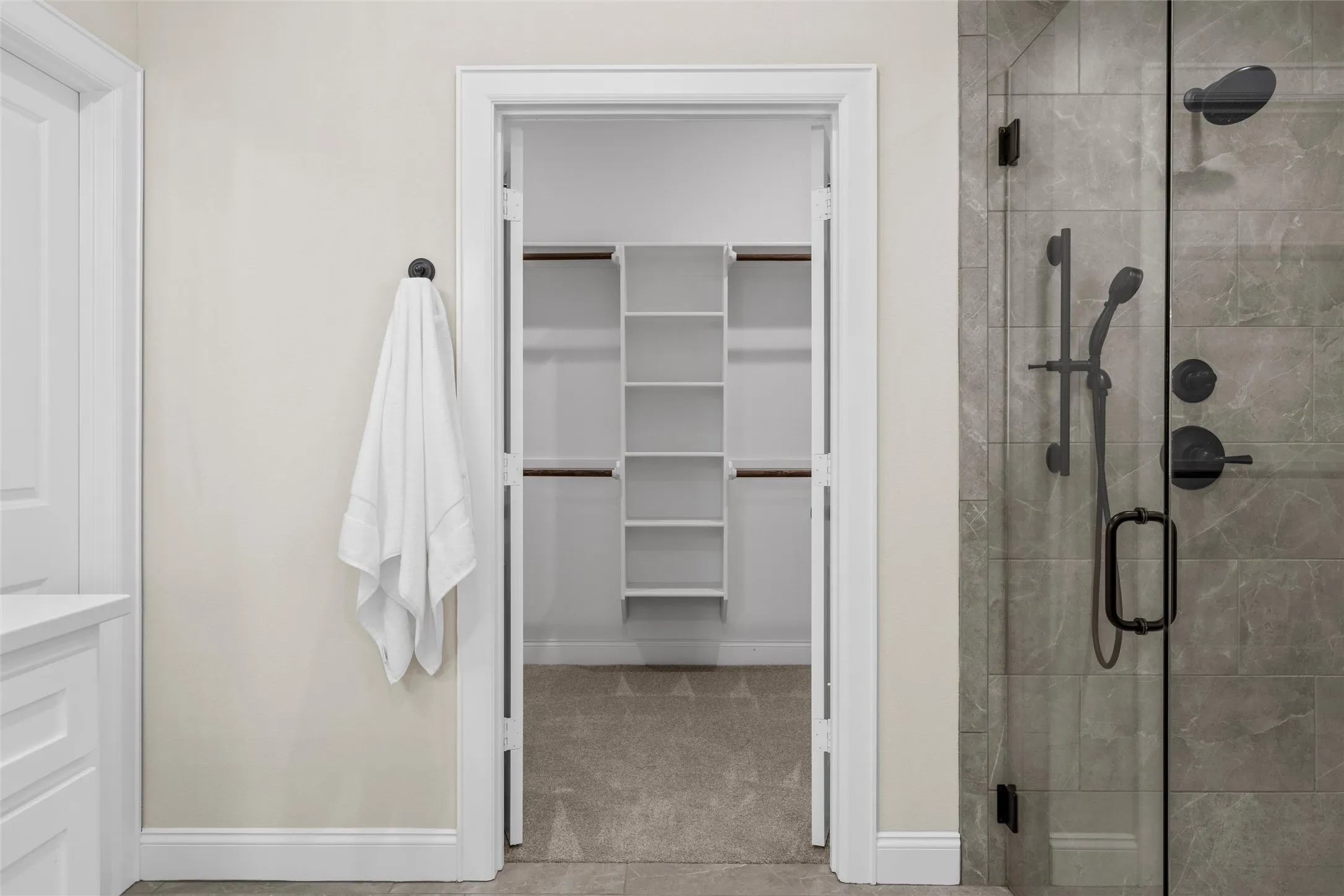 Glass-enclosed shower with matte black fixtures, tile-surround shower, and built-in shelving