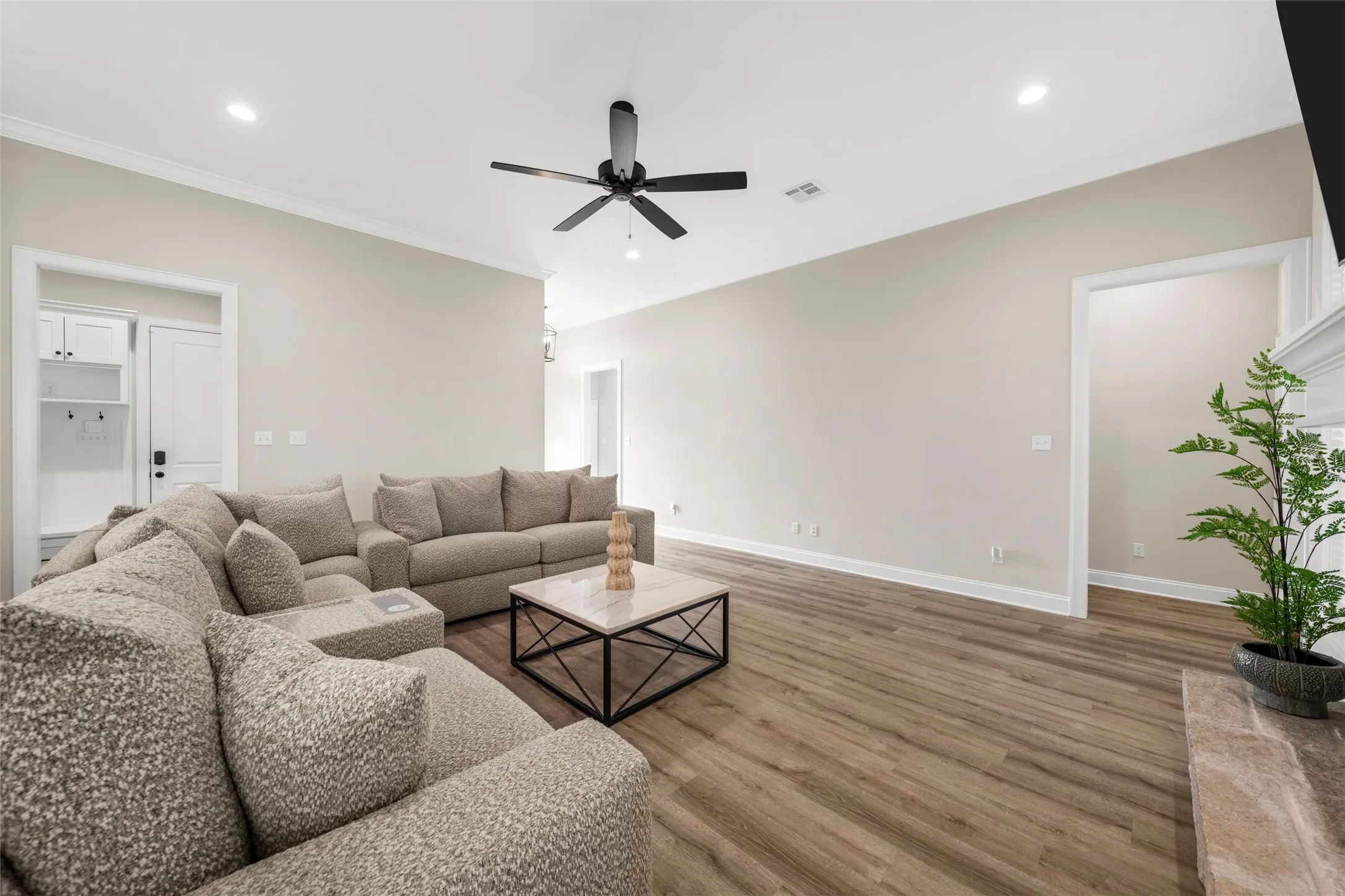 Expansive living area featuring vaulted ceilings, recessed lighting, a modern ceiling fan, wood-finish flooring, and a built-in mudroom bench with cabinetry
