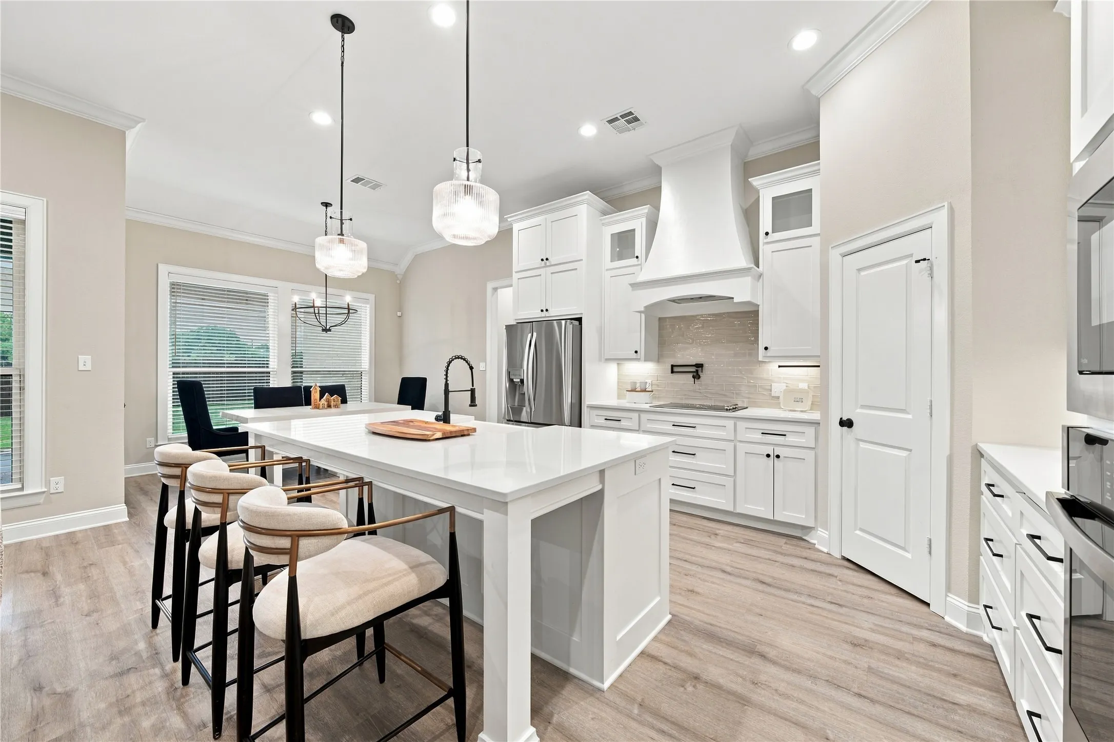 Kitchen featuring white cabinetry, wood-finish flooring, a central island with a sink, stainless steel appliances, and recessed lighting