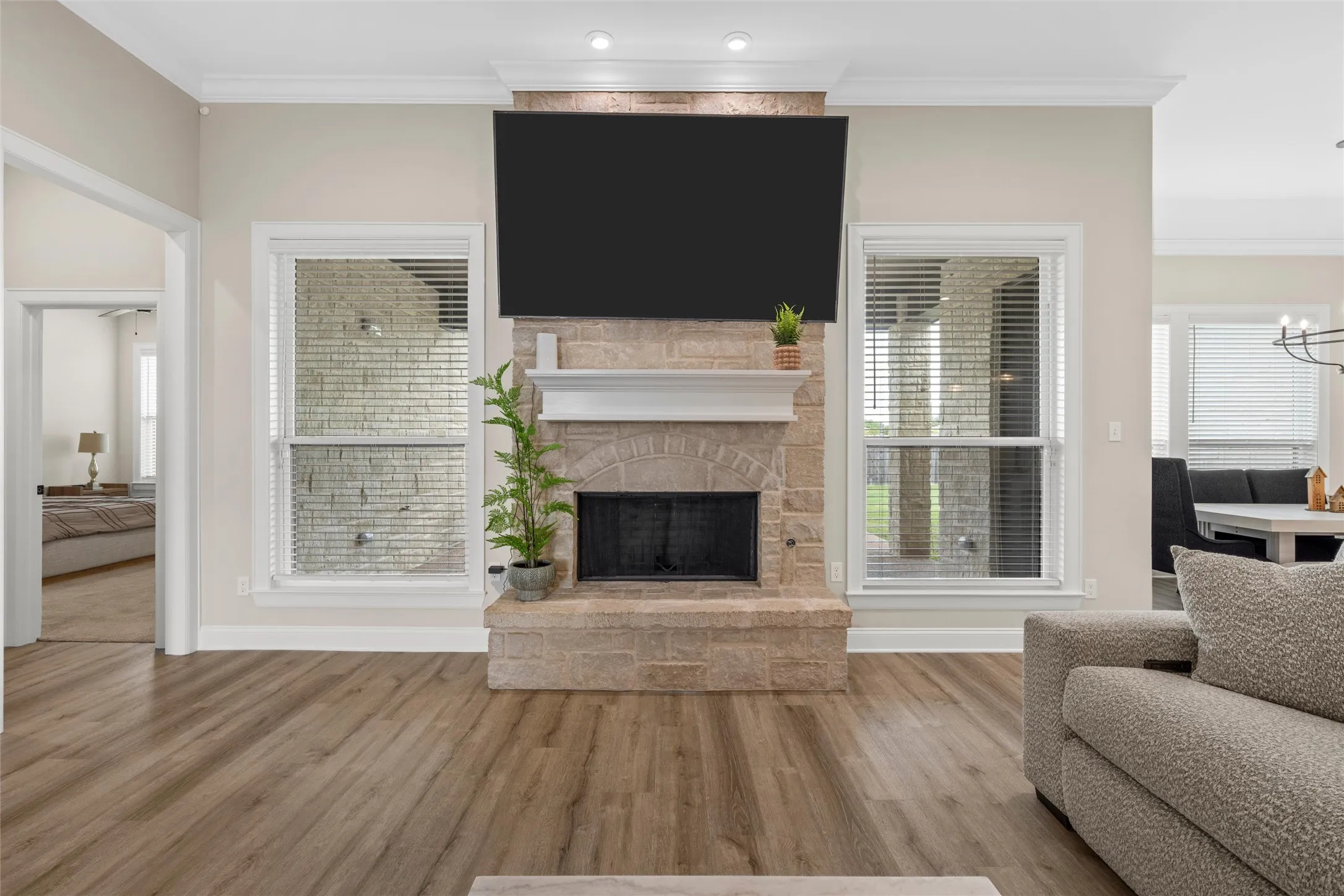 Stone fireplace with a white mantel, wood-finish flooring, recessed lighting, and crown molding