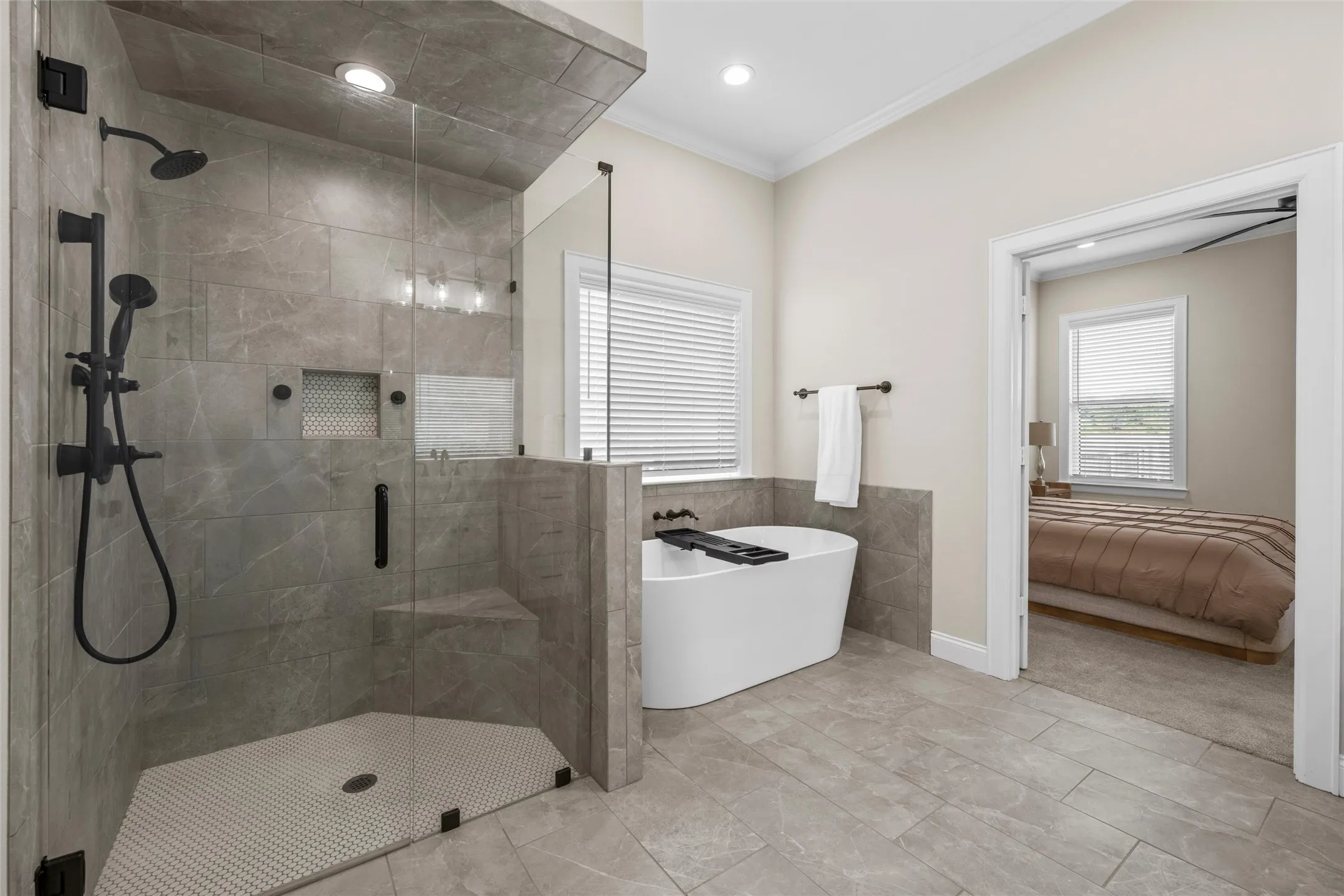 Spacious bathroom featuring a glass-enclosed shower with matte black fixtures, a built-in shower bench, and a freestanding soaking tub