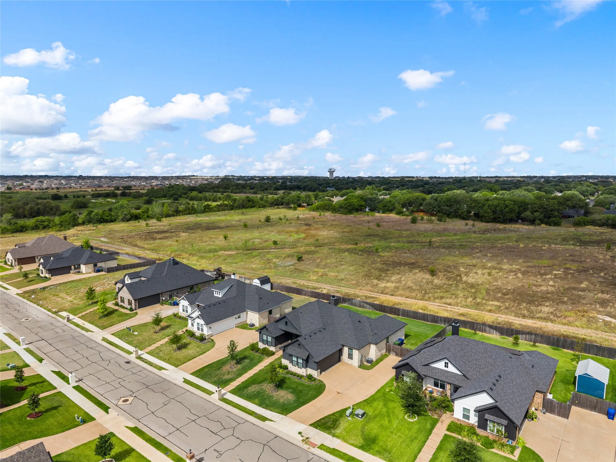 Residential street with single-story homes featuring dark shingle roofs, landscaped front yards, and paved driveways
