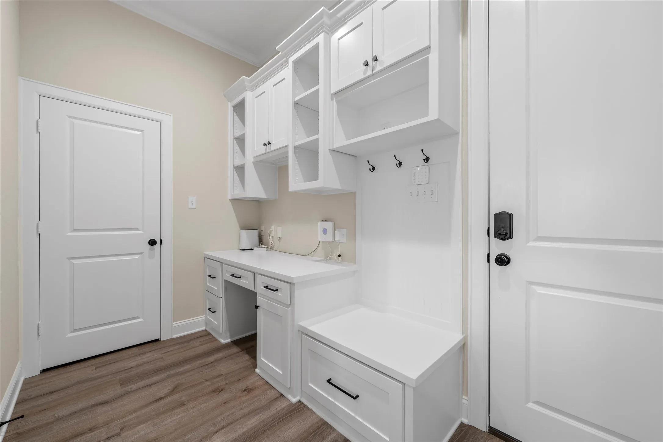 Built-in white cabinetry with open shelving, integrated desk, and storage bench