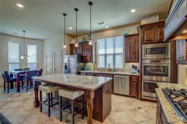 Gourmet kitchen with rich wood cabinetry, stainless steel appliances, granite countertops, and tile flooring