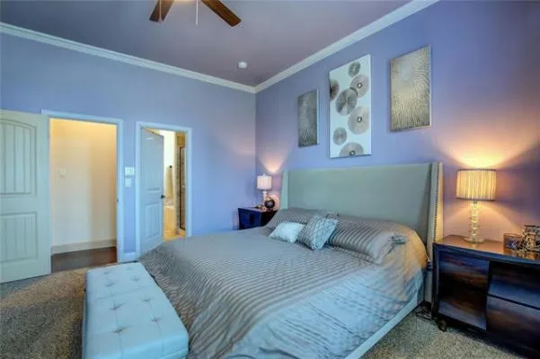 Recessed ceiling with a fan light fixture, crown molding, two panel interior doors, and carpet flooring