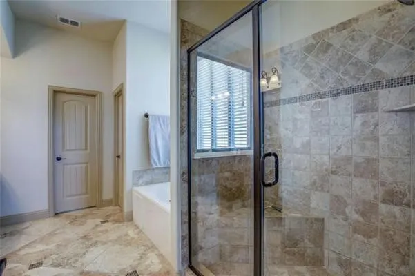 Walk-in shower with clear glass enclosure, tiled walls, and built-in shelf