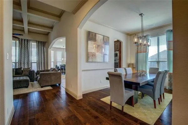 Hardwood-finish flooring throughout, coffered ceiling detail, arched doorways, and a modern chandelier