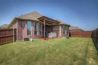 Expansive backyard featuring a manicured lawn, full privacy fencing, and a covered patio with a wood pergola
