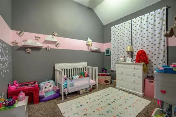 Vaulted ceiling, two-tone wall paint, white wood crib, white dresser, and wall-mounted shelving
