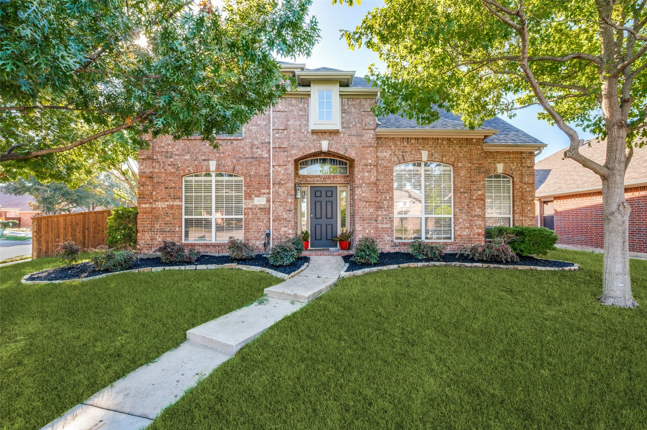 Brick exterior with arched windows, dark gray front door, and a concrete pathway