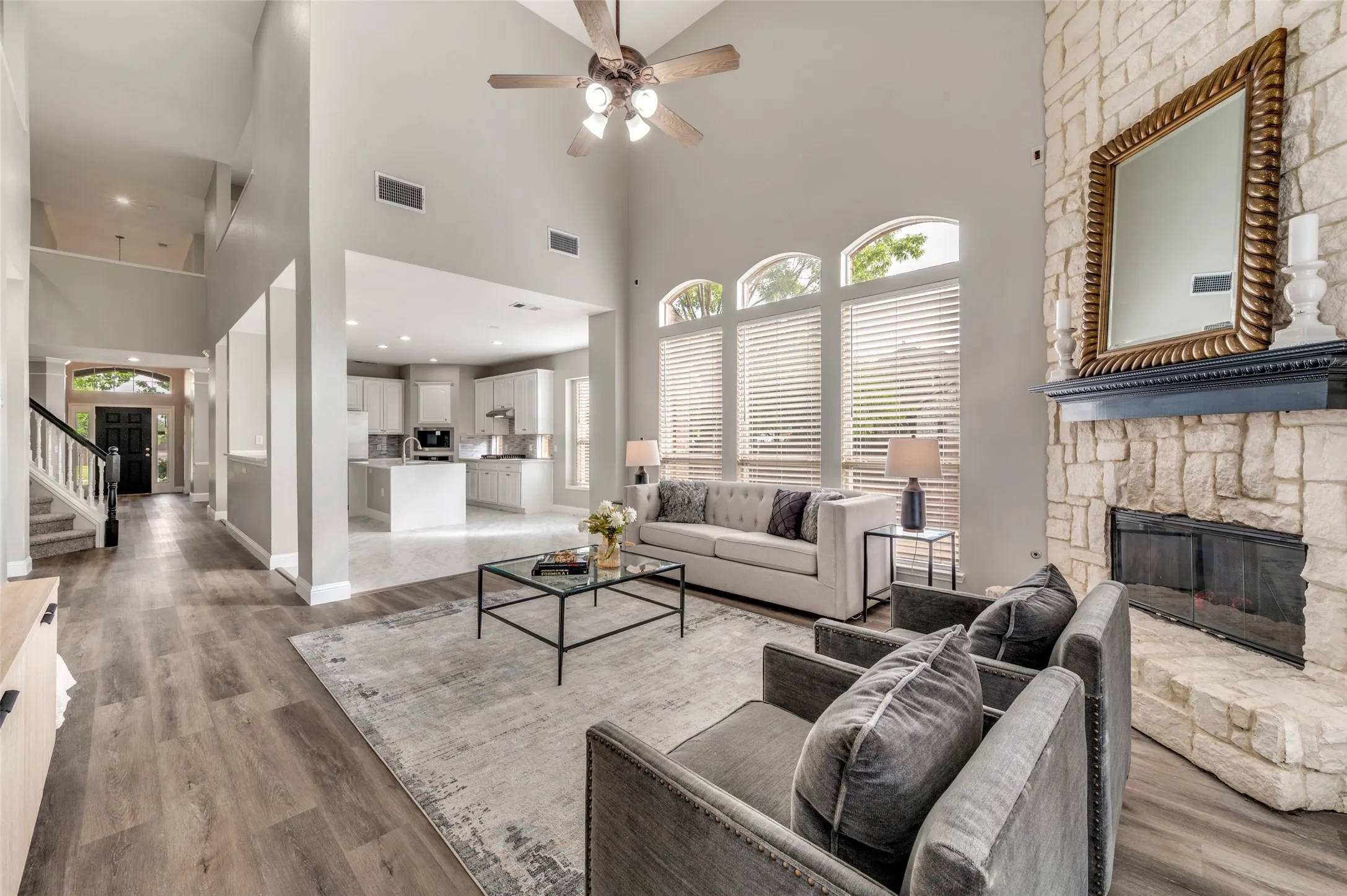 Two-story living area with high ceilings and a ceiling fan