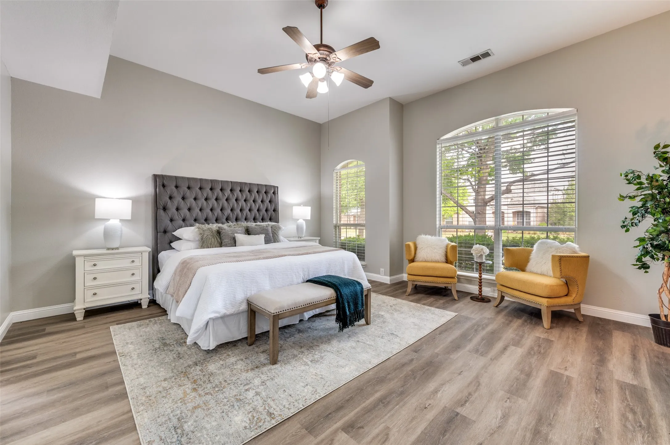 Vaulted ceiling with a ceiling fan, wood-finish flooring, two arched windows, and white window blinds