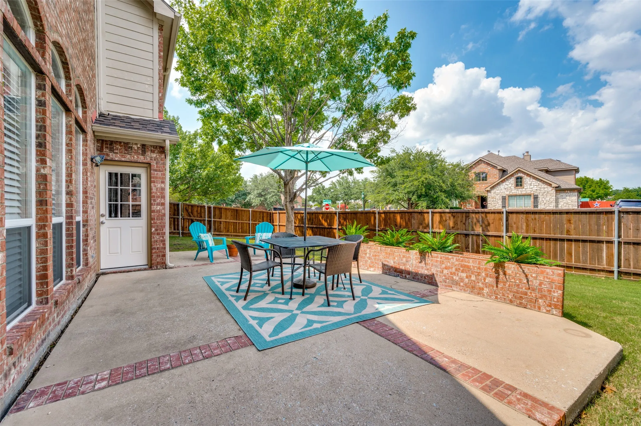 Expansive concrete patio with brick trim, brick planter boxes, and a wood privacy fence