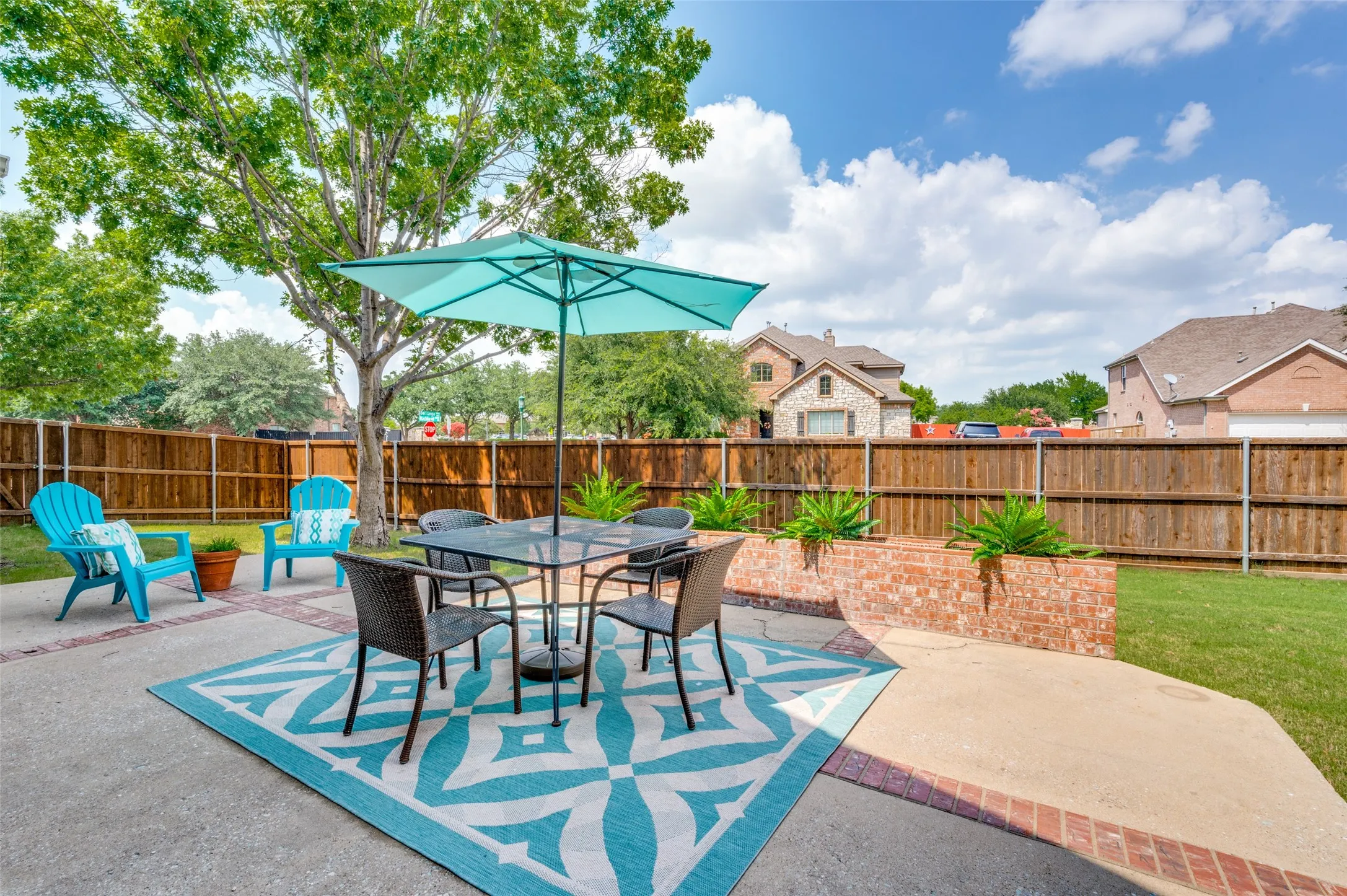 Expansive concrete patio with brick accents, wood privacy fencing, and a brick planter box