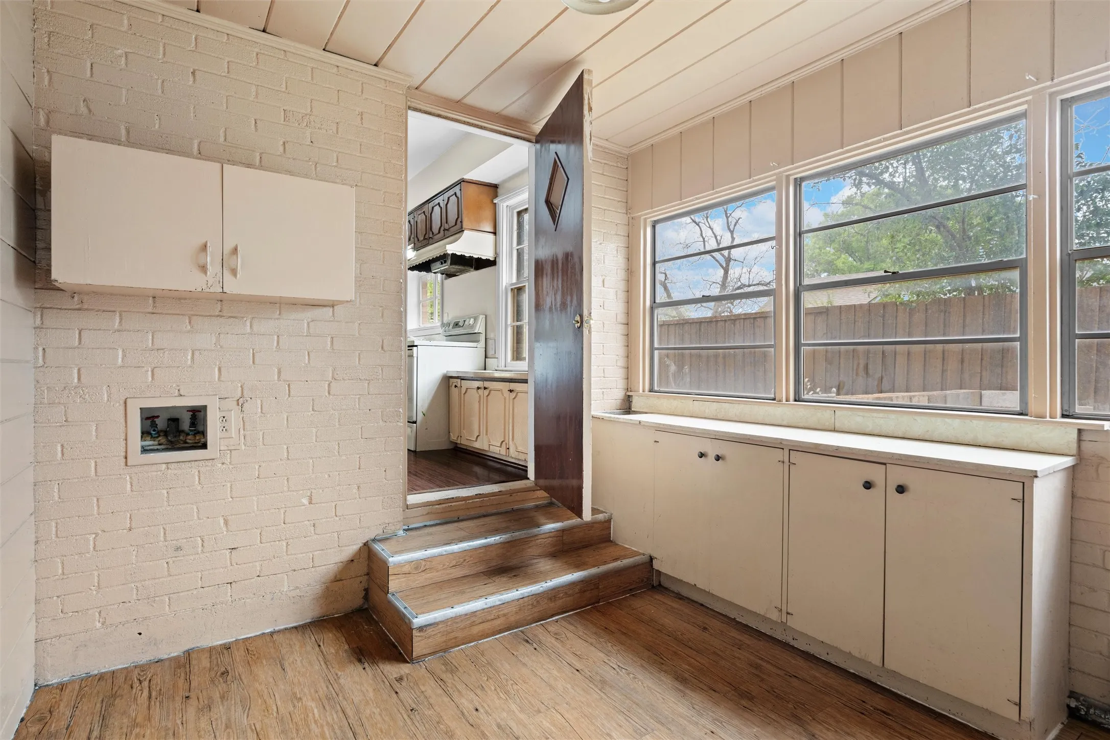 Wood-finish flooring, painted brick wall, built-in wall cabinetry, built-in window cabinetry with countertop, and multiple windows