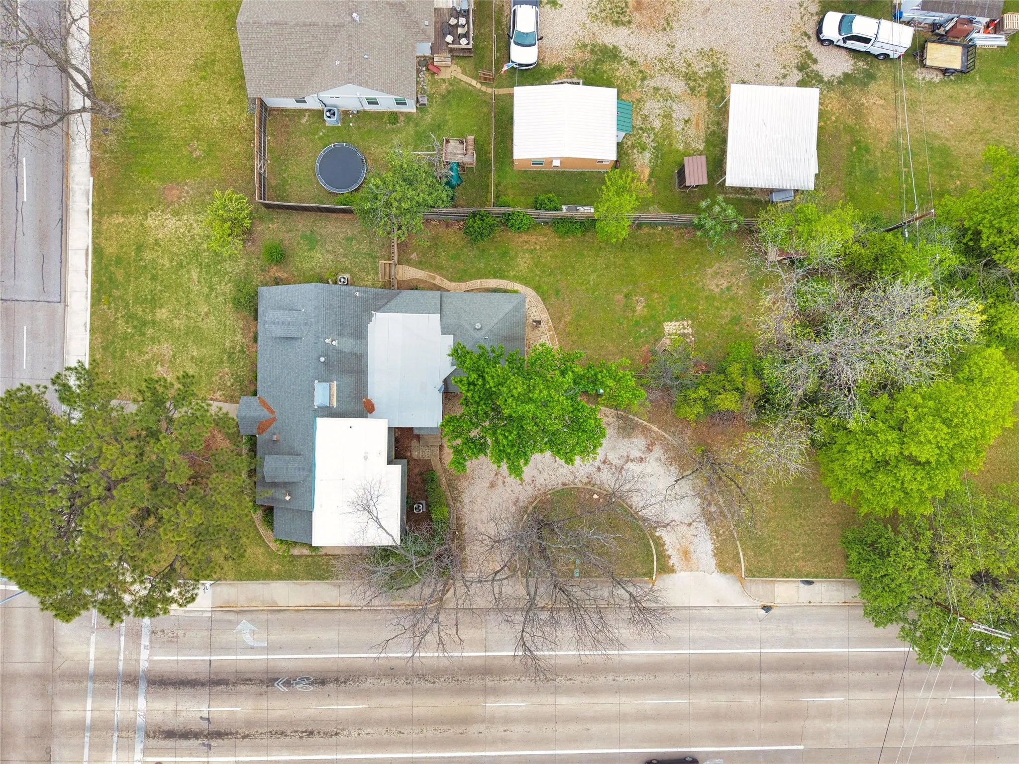 Gable roofline, mature trees, green landscaping, asphalt driveway, concrete sidewalk