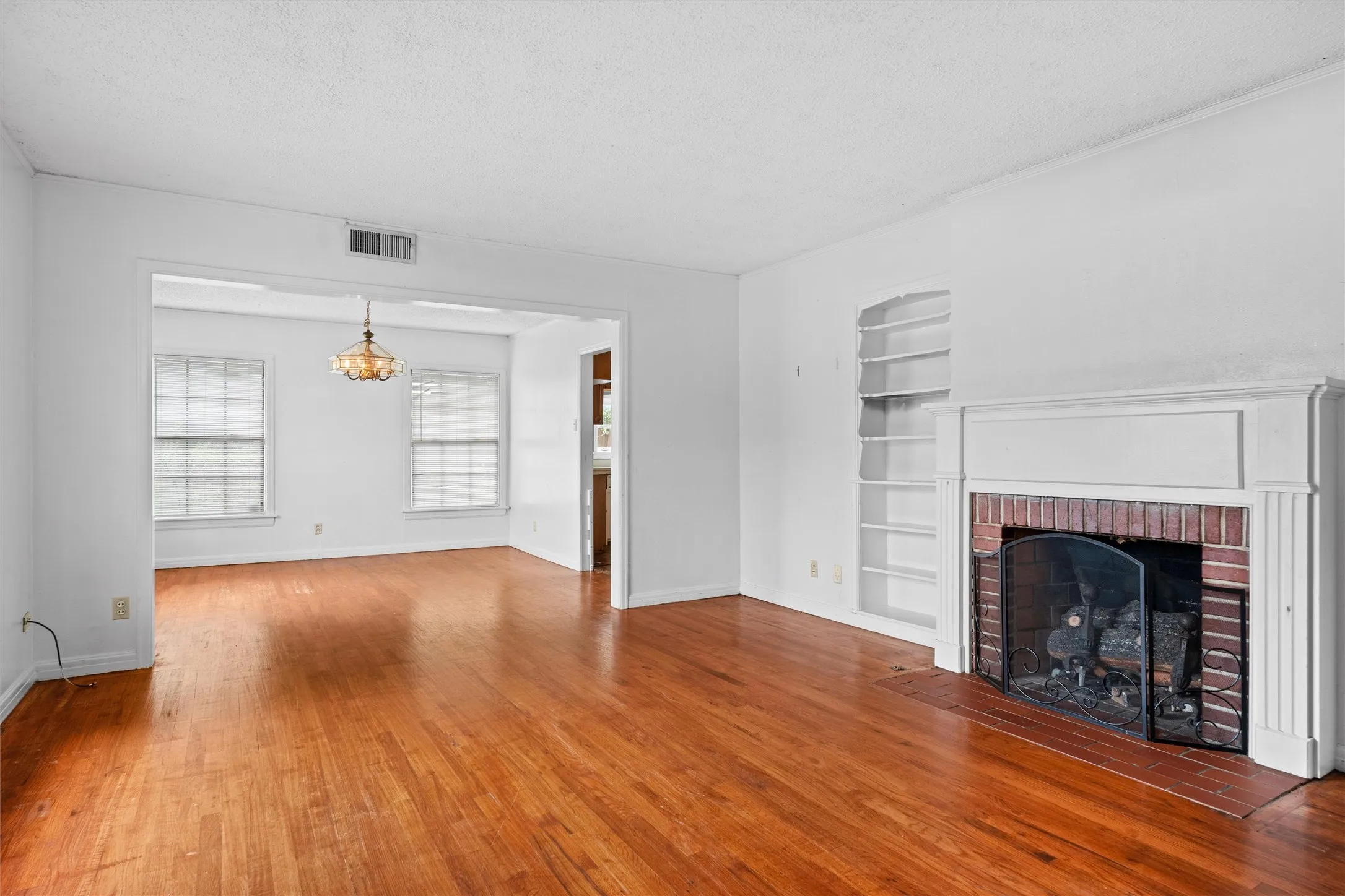 Hardwood flooring throughout, brick fireplace with mantel, built-in shelving, and transom windows