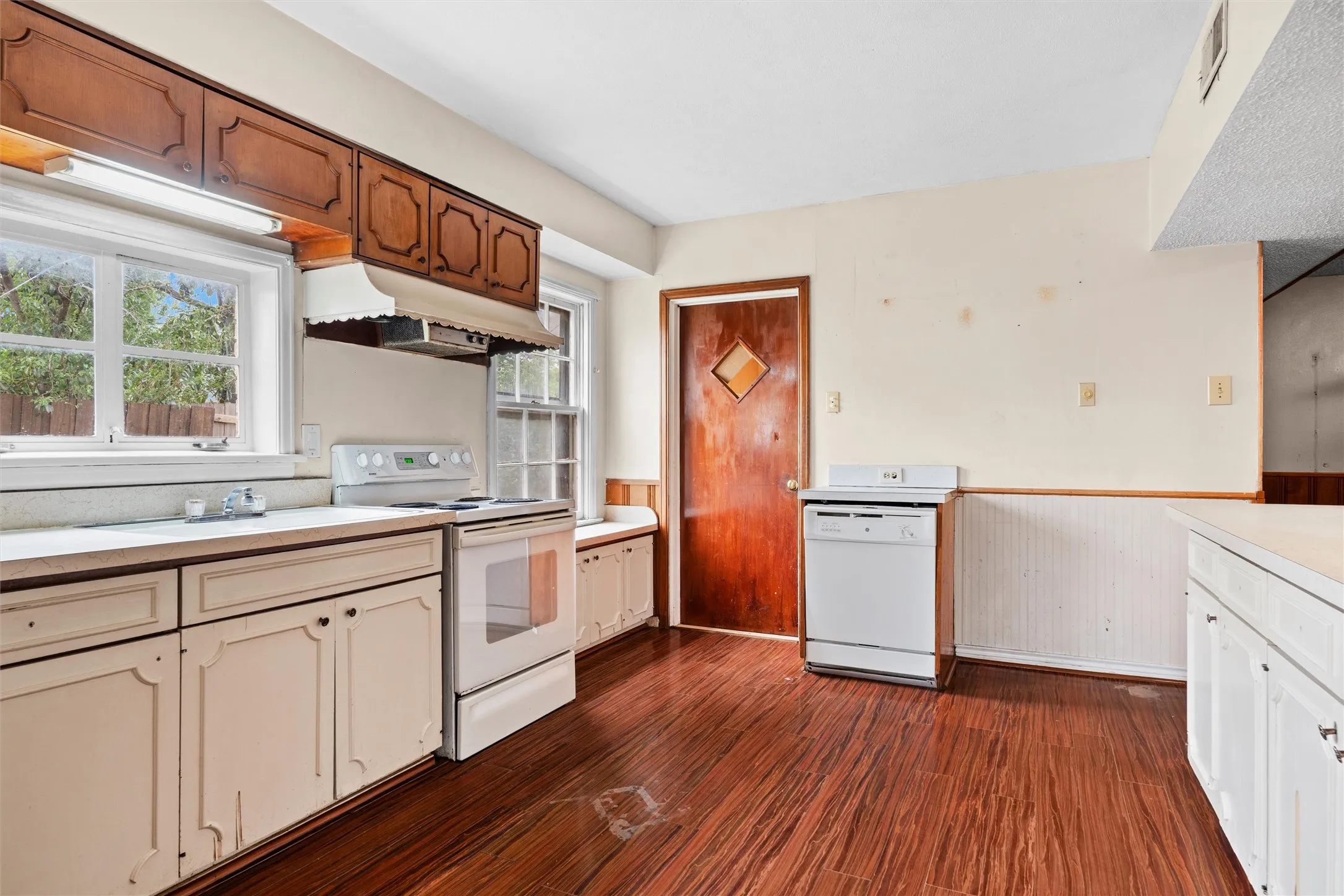 Kitchen featuring wood-finish flooring, built-in window seating, white appliances, and wood cabinetry