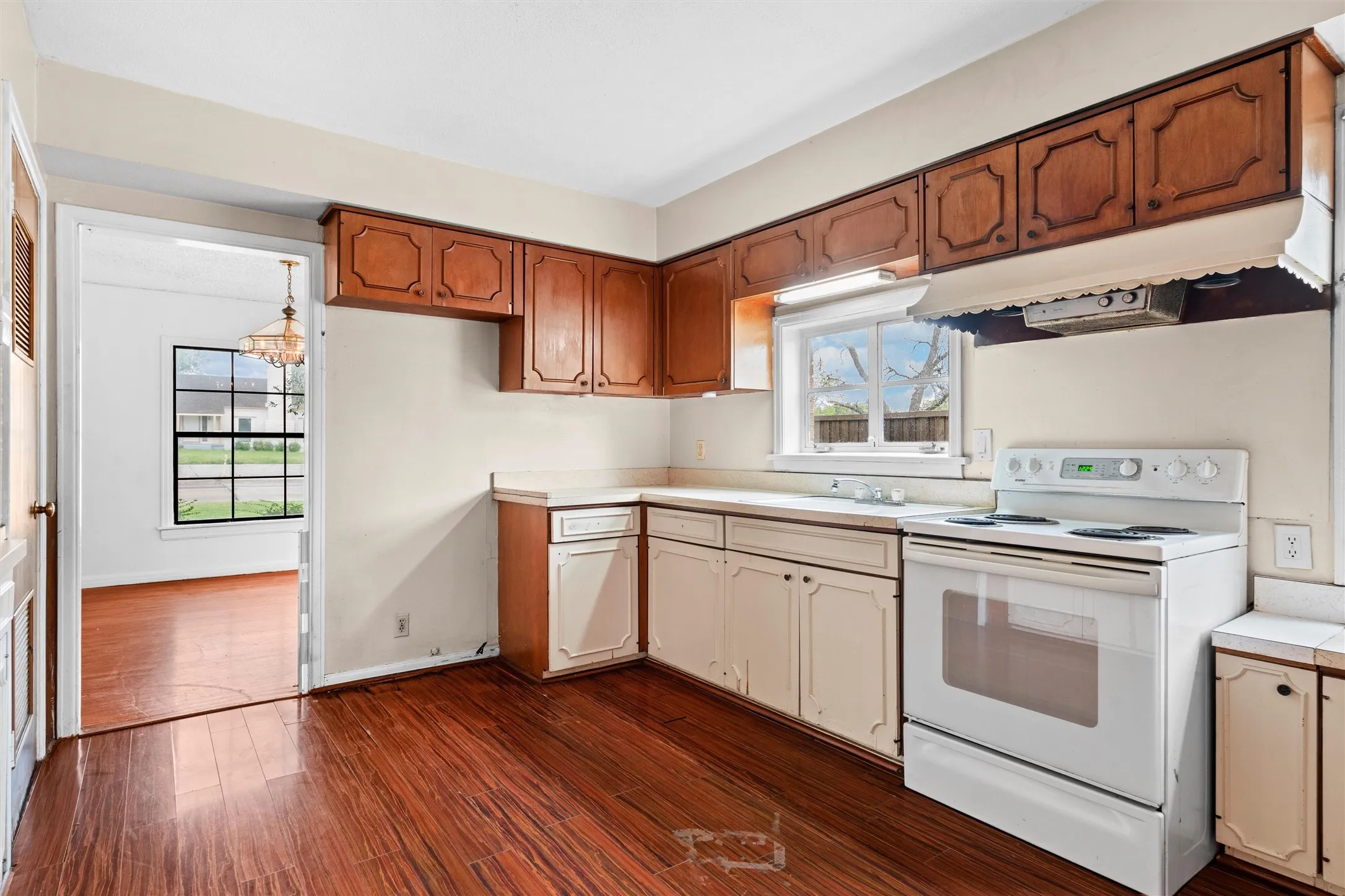 Kitchen featuring wood-finish flooring, wood cabinetry, white countertops, and white appliances