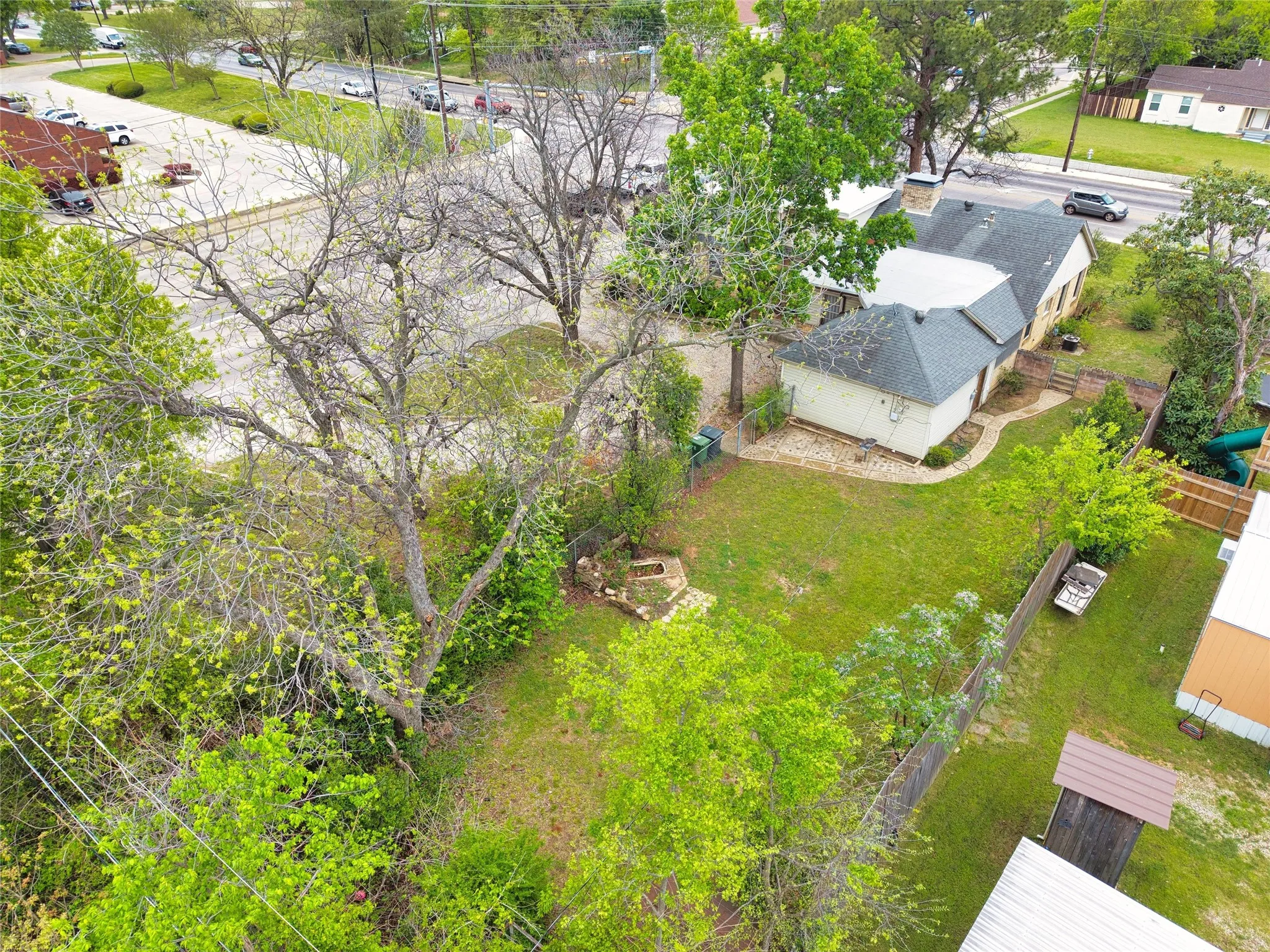Expansive backyard with a manicured lawn, established trees, and a stone-edged fire pit