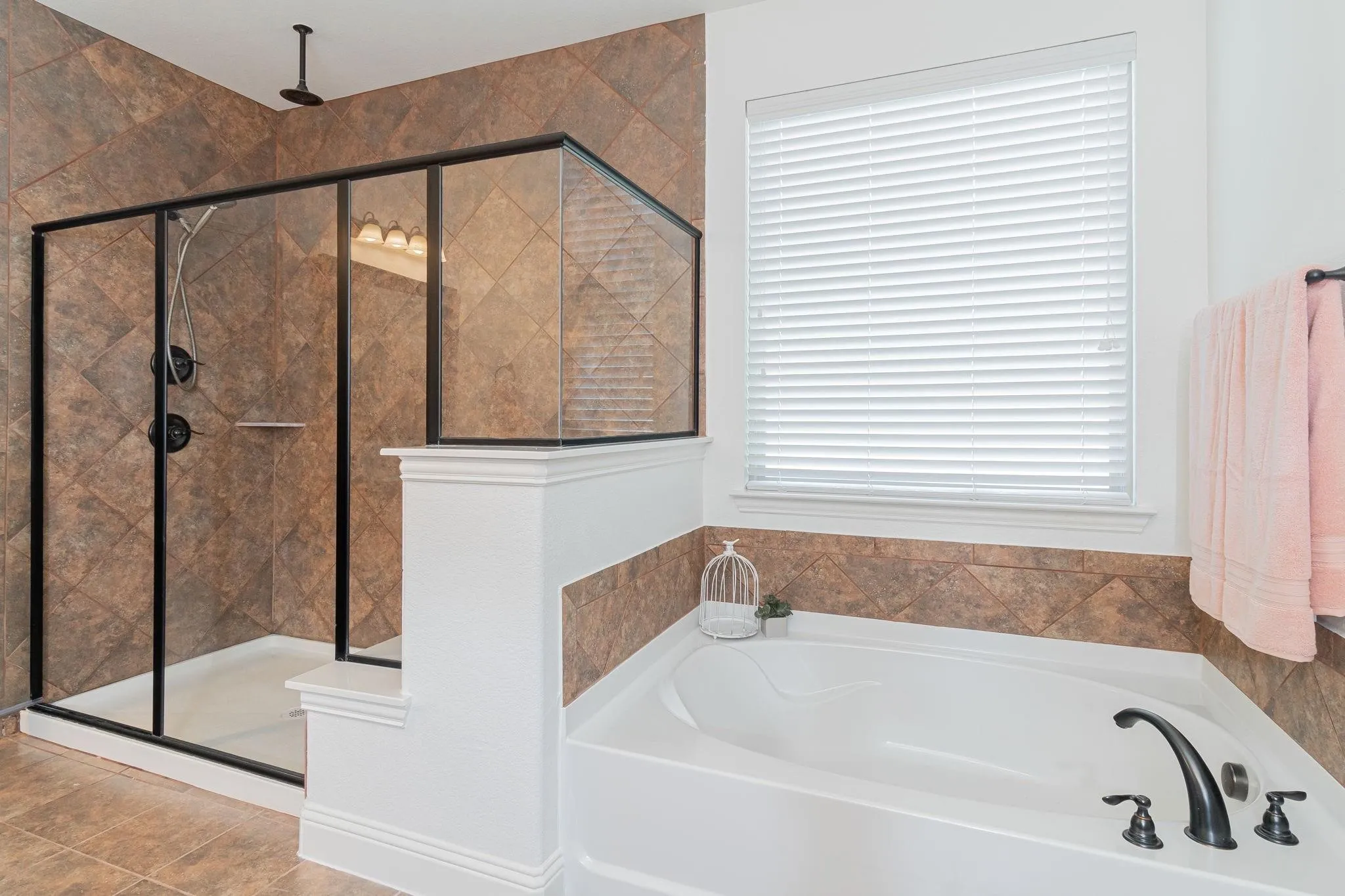 Walk-in shower with black-framed glass enclosure, built-in shower shelf, and ceiling-mounted rain shower head