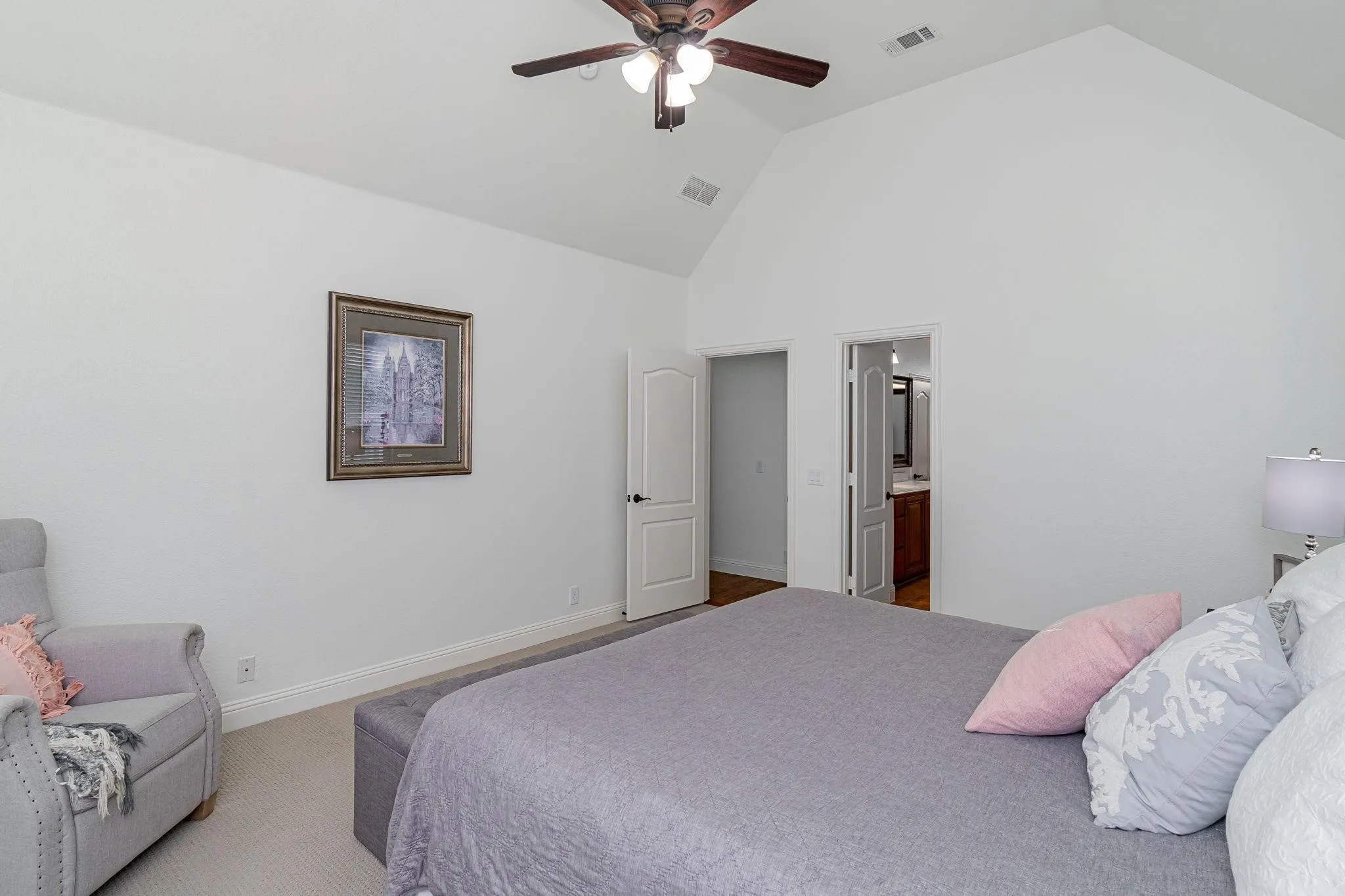 Vaulted ceiling with a ceiling fan, white paneled doors, and light-colored carpet flooring