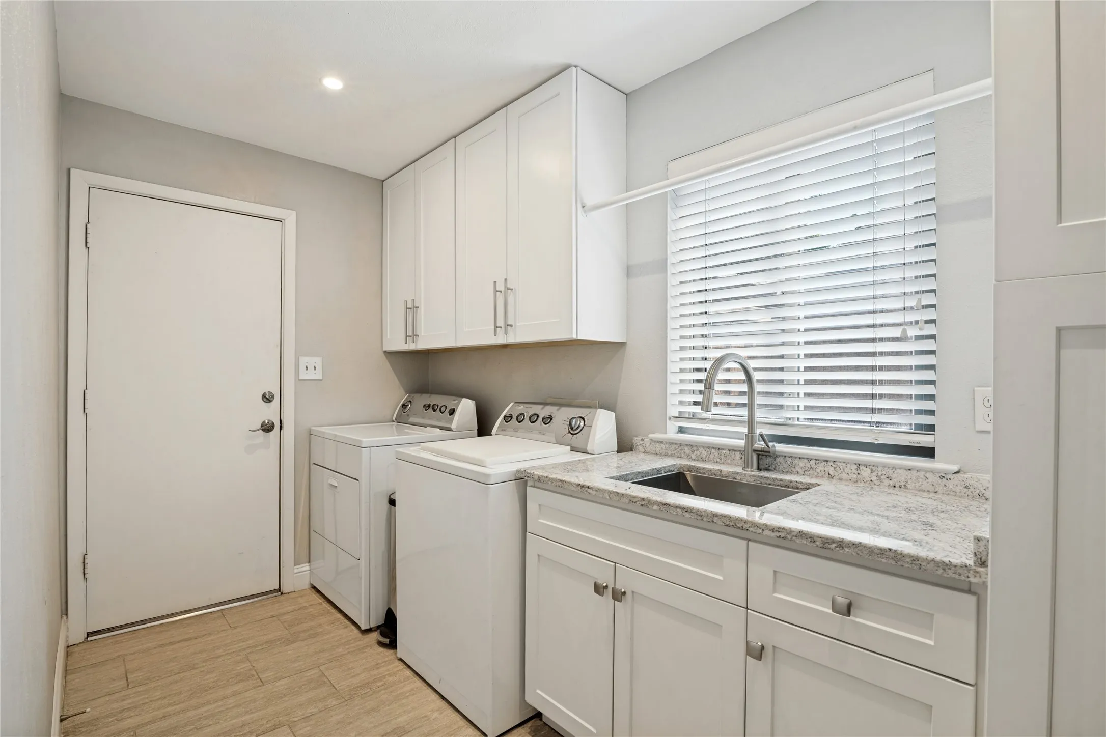 Utility Room with window, sink, and lots of storage leads to the 2-car attached garage with epoxy floor.