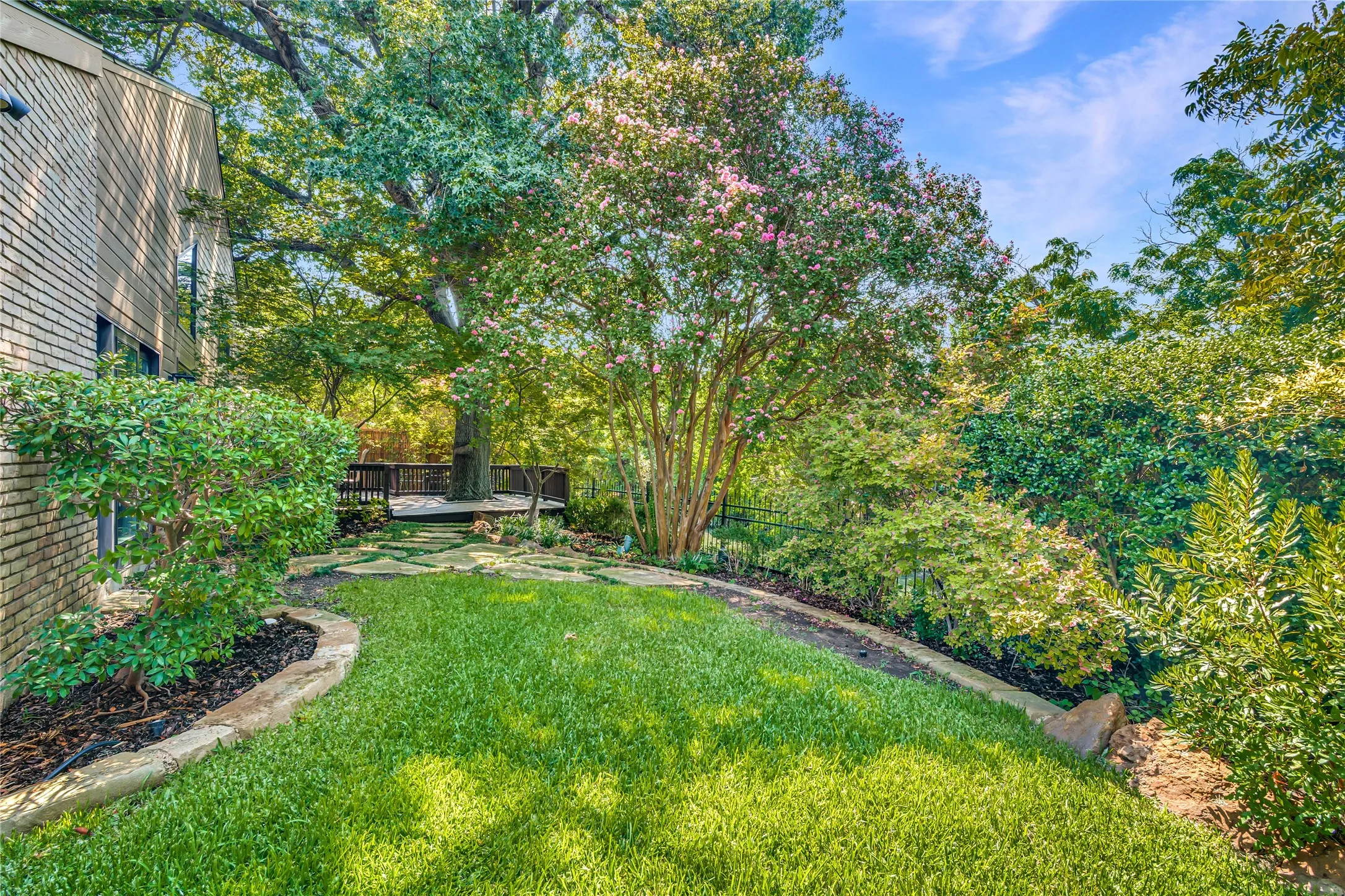 Beyond the deck is a beautifully landscaped yard.