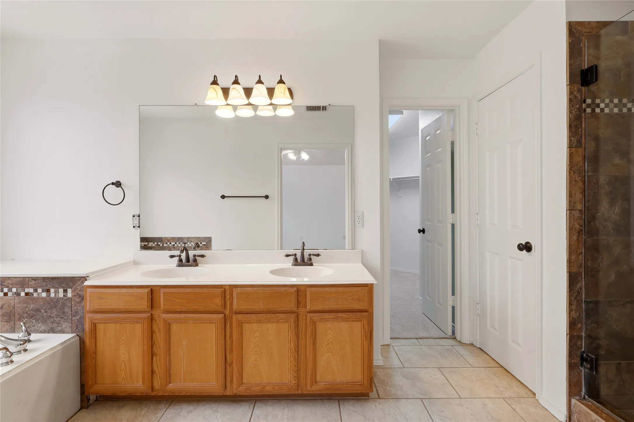Dual vanity with integrated sinks, wood cabinetry, and a full-width mirror