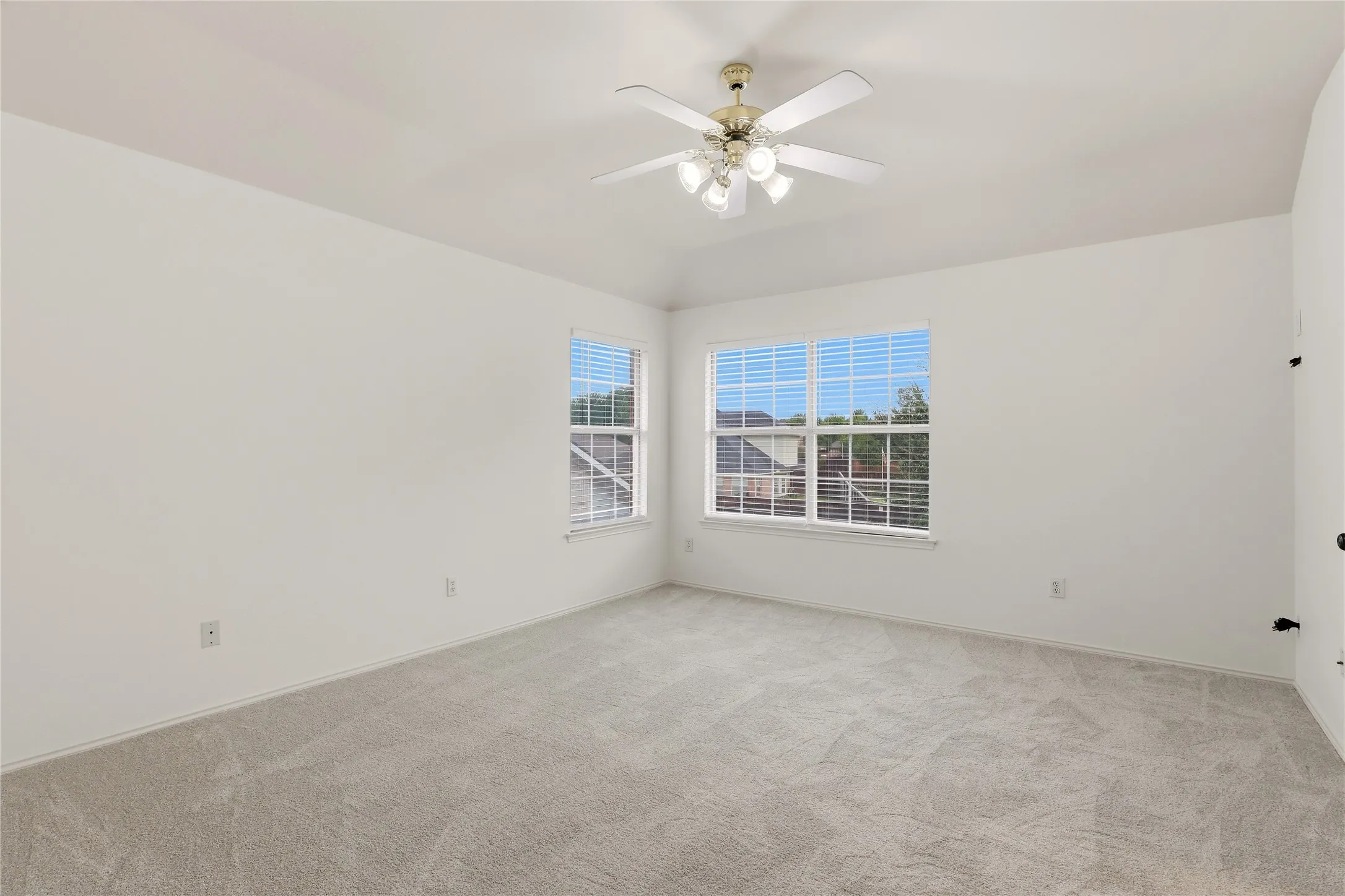 Room featuring carpet flooring, two windows with blinds, and a ceiling fan with integrated lighting