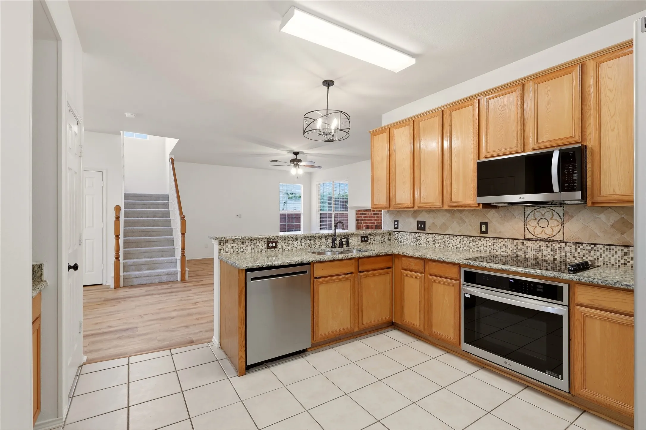Kitchen featuring wood cabinetry, stainless steel appliances, granite countertops, and tiled flooring