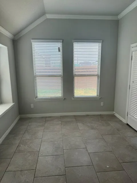 Vaulted ceiling with crown molding, two windows with blinds, built-in window bench, tile flooring, and a paneled door