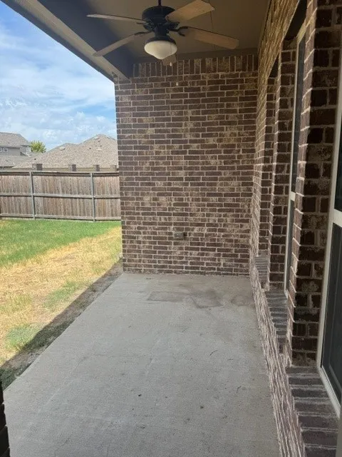 Covered patio with a concrete surface, brick exterior wall, and ceiling fan