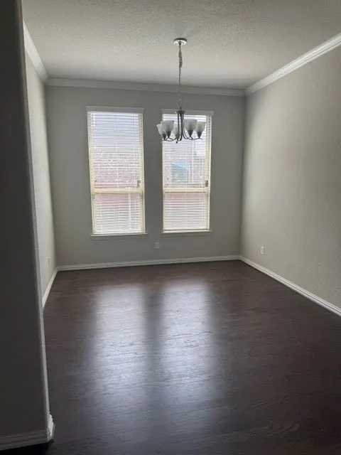 Wood-finish flooring, crown molding, and a five-light chandelier